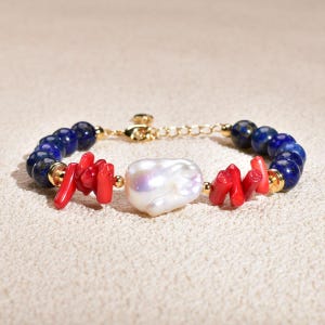 Puede incluir: Una pulsera que presenta una gran perla barroca blanca central, flanqueada por grupos de cuentas de coral rojo brillante, seguidas de cuentas redondas de lapislázuli azul profundo, todo acentuado con pequeños espaciadores dorados y un cierre de cadena.
