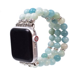 May include: A light blue and white beaded Apple Watch band with silver accents. The band is made of multiple strands of beads and has a metal clasp.