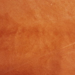 Puede incluir: Primer plano de una superficie de cuero texturizada de color naranja-marr&oacute;n.