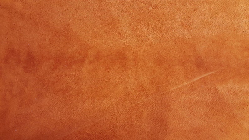 Puede incluir: Primer plano de una superficie de cuero texturizada de color naranja-marr&oacute;n.