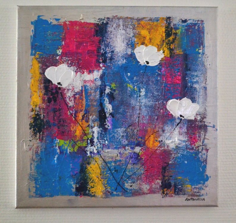 May include: Abstract painting with white flowers on a colorful background of blue, yellow, pink, and red. The artist's signature, Antonella, is in the bottom right corner.
