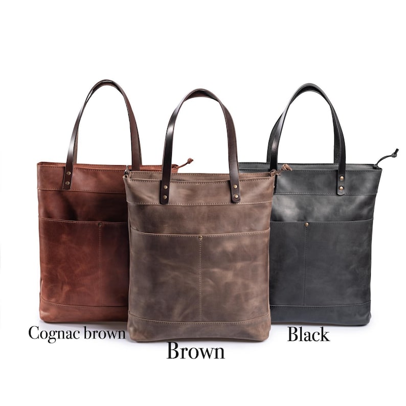 May include: Three leather tote bags in different colors: cognac brown, brown, and black. Each bag has a zipper closure, two front pockets, and a top handle.