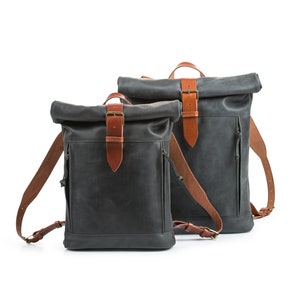 May include: Two black leather roll-top backpacks with brown leather straps and buckles.