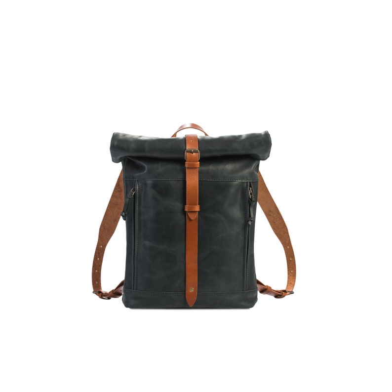 May include: A black leather backpack with a roll-top closure and brown leather straps. The backpack has a buckle closure and a zipped pocket on the front.