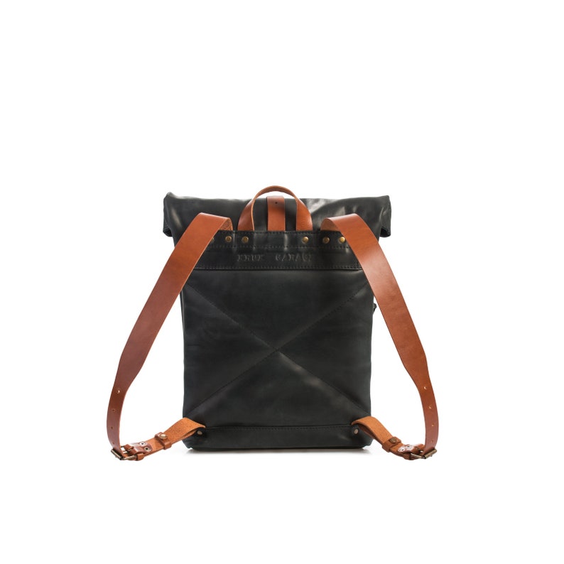 May include: Black leather backpack with brown leather straps and buckles. The backpack has a roll-top closure and a flap with the text "FRUIT CAVAN" embossed on it.