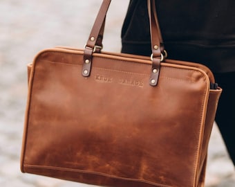 Op de afbeelding: Een bruine leren tote bag met een bovenste handvat en een