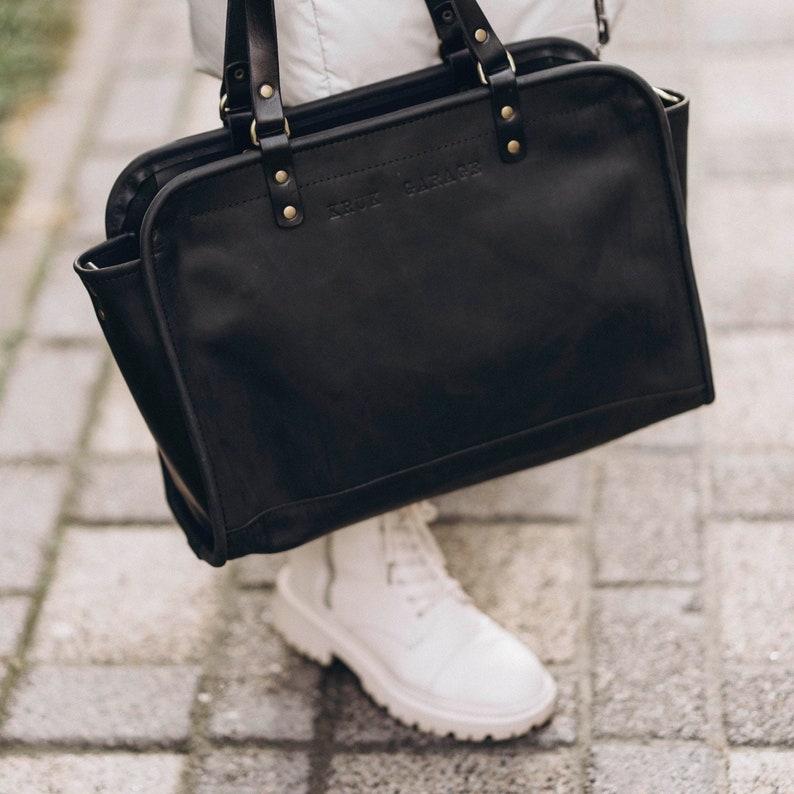 May include: A black leather tote bag with the text "KRUT GARAGE" embossed on the front.