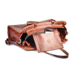 May include: A brown leather travel bag with a zippered pocket and a small phone pocket. The bag has a top handle and a shoulder strap.