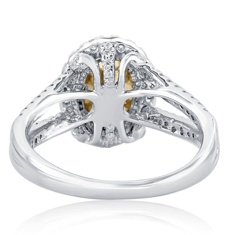 May include: A silver-toned ring featuring a split shank design adorned with small clear stones. The center setting holds a yellow stone, surrounded by a halo of clear stones, with additional clear stones embedded along the band's split arms.