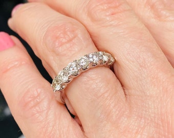 May include: A silver band ring with a row of round, clear diamonds set in a pave setting.
