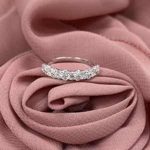 May include: A silver-toned band ring featuring a row of small, clear, round-cut stones set across the top half. The metal band has a polished finish and the interior of the ring shows a small, partially visible hallmark engraving.