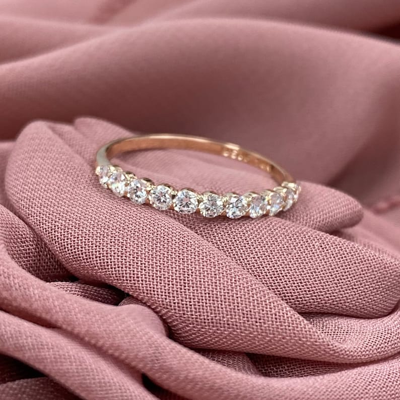 Pu&ograve; includere: Un delicato anello a fascia d'oro con una fila di diamanti rotondi scintillanti.