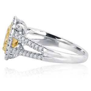 May include: A silver-toned ring featuring a large, oval-cut yellow center stone surrounded by a halo of small, clear white stones. The split shank band is also encrusted with rows of small, clear white stones along the sides.