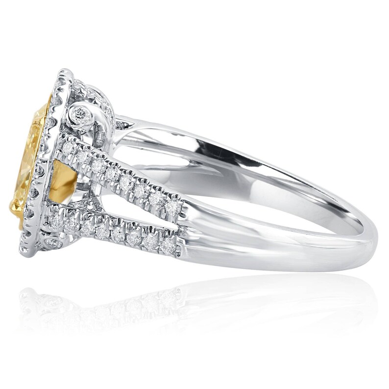 May include: A silver-toned ring featuring a large, oval-cut yellow center stone surrounded by a halo of small, clear white stones. The split shank band is also encrusted with rows of small, clear white stones along the sides.