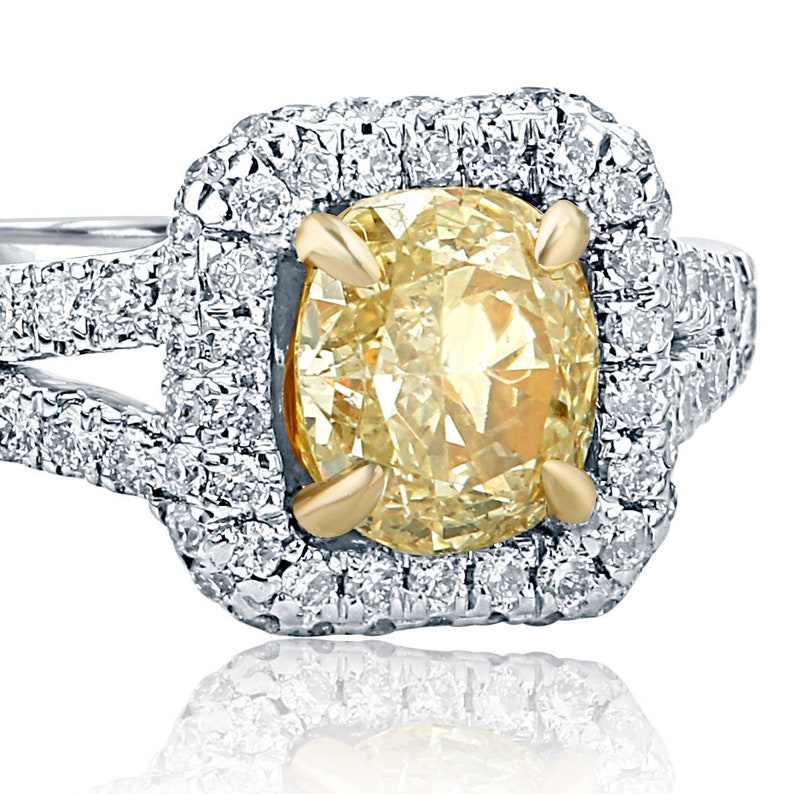 May include: A yellow diamond engagement ring with a double halo of smaller diamonds. The ring is set in white gold with a yellow gold band.