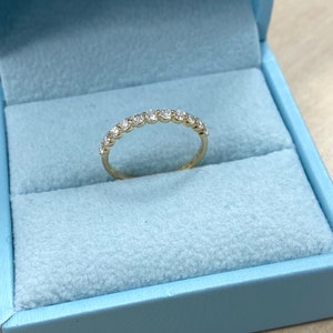 Pu&ograve; includere: Un delicato anello a fascia d'oro con una fila di piccoli diamanti rotondi incastonati a pav&eacute;.