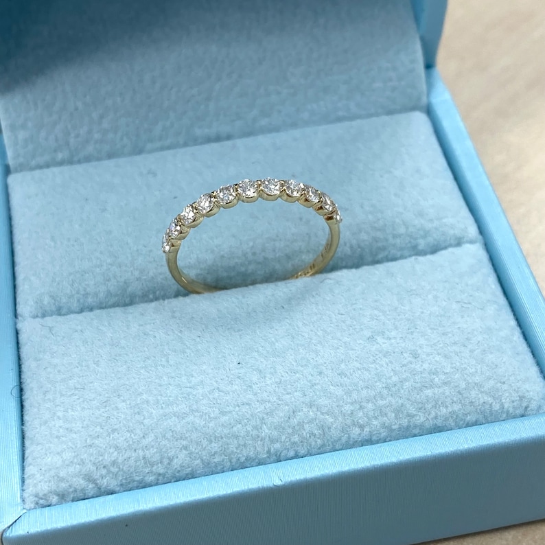 Pu&ograve; includere: Un delicato anello a fascia d'oro con una fila di piccoli diamanti rotondi incastonati a pav&eacute;.
