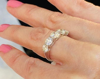 May include: A silver band ring with five round, clear gemstones set in a row.