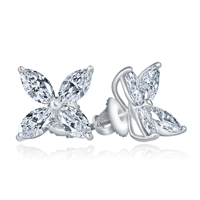 May include: A pair of silver earrings with a four-leaf clover design featuring marquise-shaped diamonds.