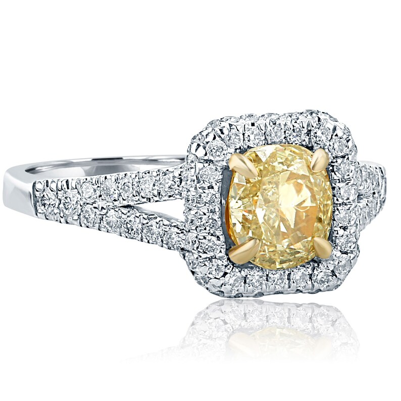 May include: A yellow gold and white gold engagement ring with a large, oval-shaped, yellow diamond center stone. The center stone is surrounded by a halo of smaller diamonds. The band is also set with smaller diamonds.