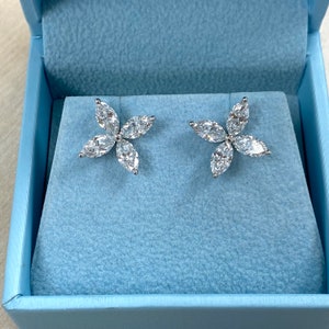 May include: A pair of silver flower-shaped earrings with clear marquise-shaped stones.