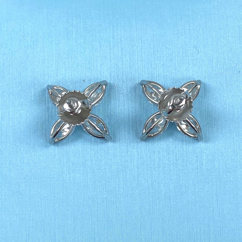 May include: A pair of silver earrings with a flower design. Each earring has five petals with a small clear stone in the center of each petal.