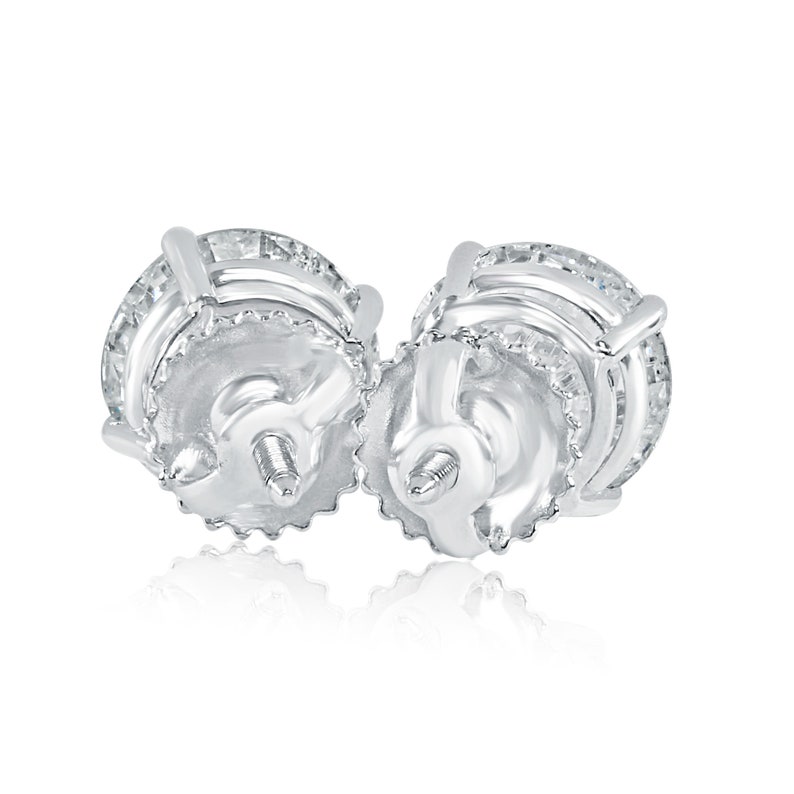 May include: A pair of silver stud earrings with a round, multi-layered design. The earrings have a screw-back closure.
