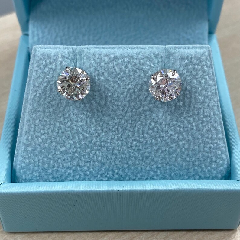 May include: A pair of round diamond stud earrings in a light blue velvet box.