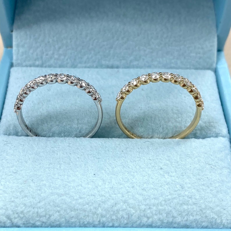 Pu&ograve; includere: Due fedi nuziali con diamanti, una in oro bianco e una in oro giallo, esposte in una scatola di velluto blu.