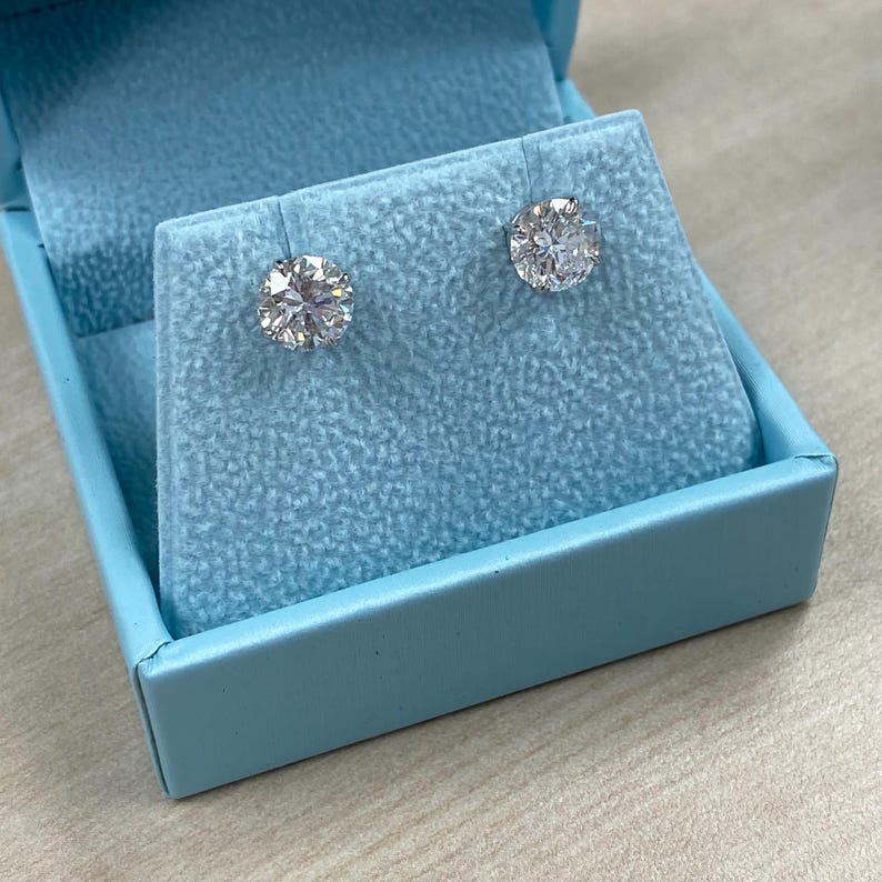 May include: A pair of diamond stud earrings in a light blue velvet jewelry box.