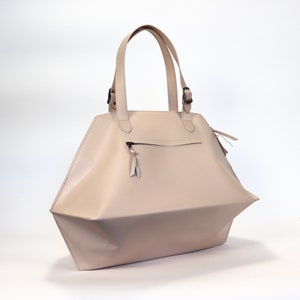 May include: A light pink leather tote bag with two top handles and a zippered pocket on the front.