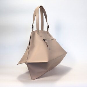 May include: A light beige tote bag with a zippered pocket and two top handles.