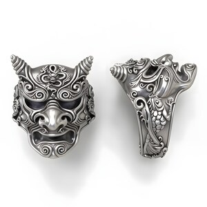 Op de afbeelding: Twee zilveren ringen met ingewikkelde ontwerpen. E&eacute;n ring is een gedetailleerd masker met hoorns, de andere ring heeft een gestileerd gezicht met sierlijke patronen. De ringen staan tegen een witte achtergrond.