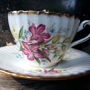 Vintage Paragon tea cup and saucer with a ribbed design featuring a thick gold trim and pink flowers