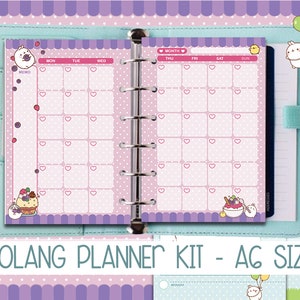 Puede incluir: Una agenda rosa y morada con un calendario mensual y una sección de notas. La agenda presenta un personaje de dibujos animados con una apariencia de conejo. El texto "MOLANG PLANNER KIT - AG SIZE" está impreso en la portada de la agenda.