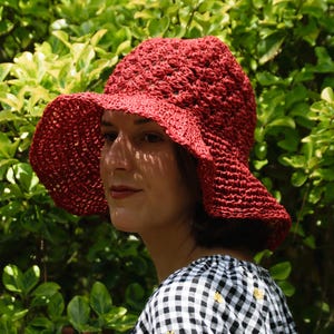 May include: A red crocheted sun hat with a wide brim. The hat is made of a lightweight, breathable material and is perfect for keeping the sun out of your eyes.