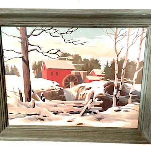 May include: A framed painting of a red gristmill in a snowy winter landscape. The mill has a water wheel and is surrounded by trees and a wooden fence.