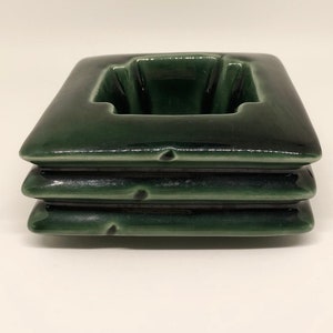 May include: A green ceramic planter with a square shape and three tiers. The planter has a smooth, glossy finish.