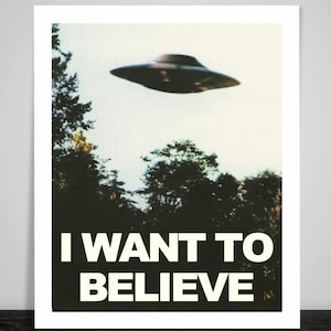 May include: A framed print featuring a vintage-style image of a flying saucer hovering above a treeline. The text "I WANT TO BELIEVE" is printed in bold white letters at the bottom of the image, set against a black background.