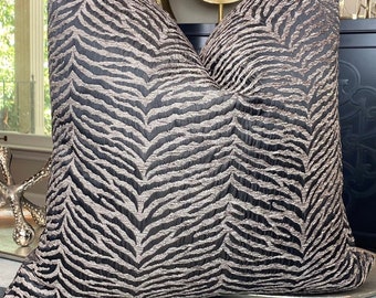 May include: A black and gold zebra patterned throw pillow with a textured fabric.