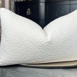 May include: White textured cushion with a subtle raised pattern. The cushion is sitting on a grey surface.