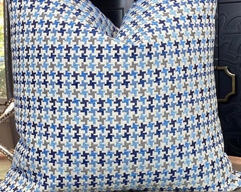May include: A blue and white patterned throw pillow with a houndstooth design sits on a grey velvet storage ottoman.