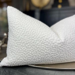 May include: White pillow with a textured, raised dot pattern. The pillow is lying on a silver tray.