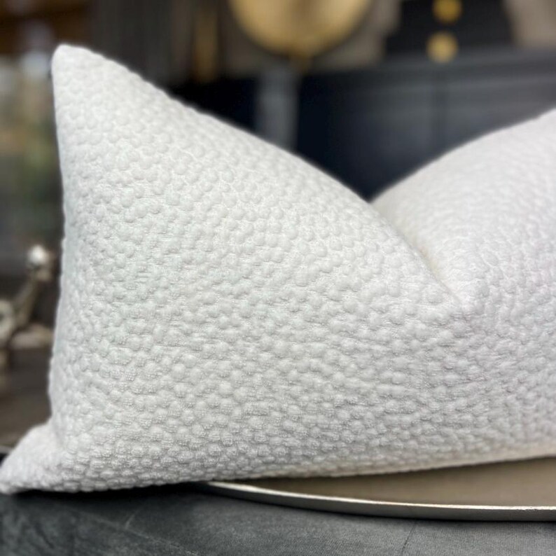 May include: White pillow with a textured, raised dot pattern. The pillow is lying on a silver tray.