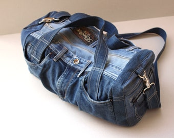 May include: A blue denim duffel bag with a zipper closure and a single strap. The bag is made from recycled denim and has a unique, handmade look.