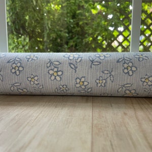 May include: A roll of blue and white floral patterned wallpaper with a subtle striped pattern.