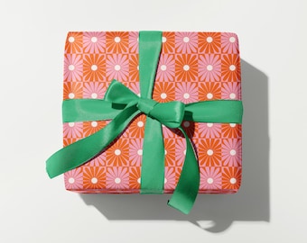 May include: A gift box wrapped in pink and orange floral patterned paper with a green satin ribbon tied in a bow.