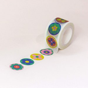 May include: A roll of white washi tape with colorful flower designs. The tape is partially unrolled, showing the repeating pattern of flowers with pink, green, blue, and yellow accents.