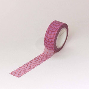 May include: A roll of pink and red patterned washi tape. The tape has a geometric design with red lines on a pink background.