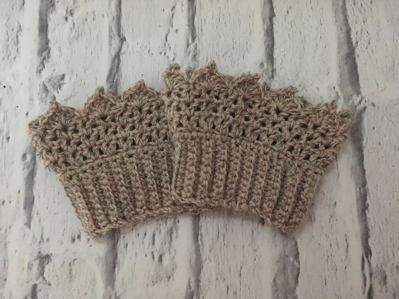 May include: A set of three crocheted beige wrist warmers with a scalloped edge.
